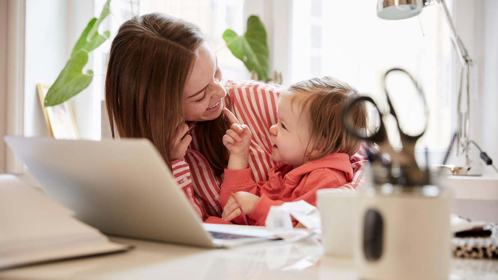 Smiling woman talking to daughter while working