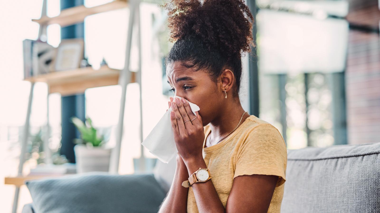 Girl blowing her nose with a tissue.