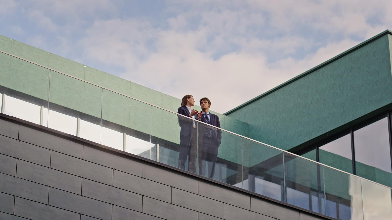 Two colleagues talk on a building balcony