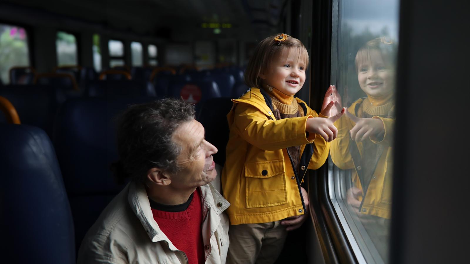 Happy child in a yellow jacket being held by his father
