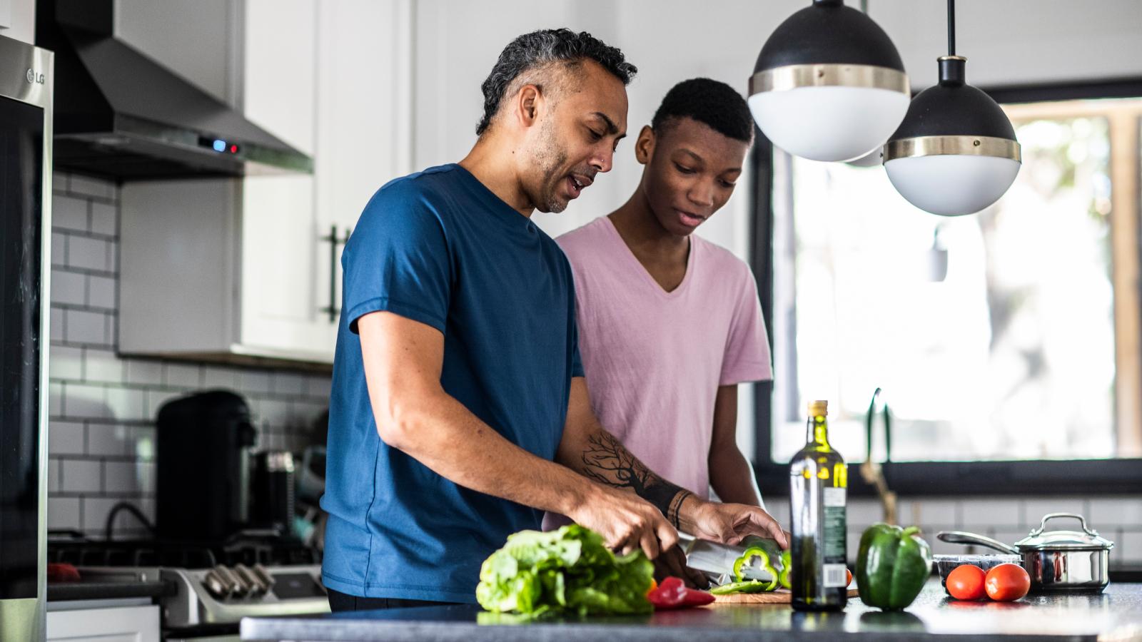 Father and teenage son cooking together.