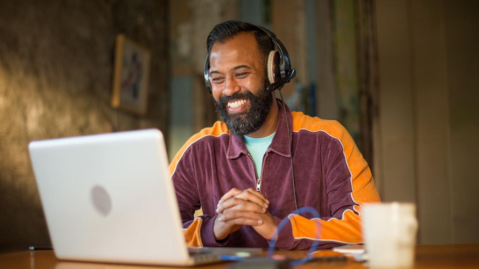 Smiling man looking at his laptop on a virtual meeting Smiling man looking at his laptop on a virtual meeting