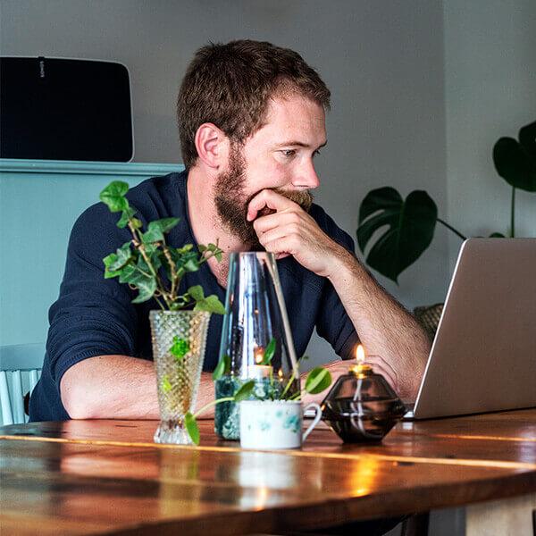 Middle aged male working from home on laptop at a table looking burnt out.