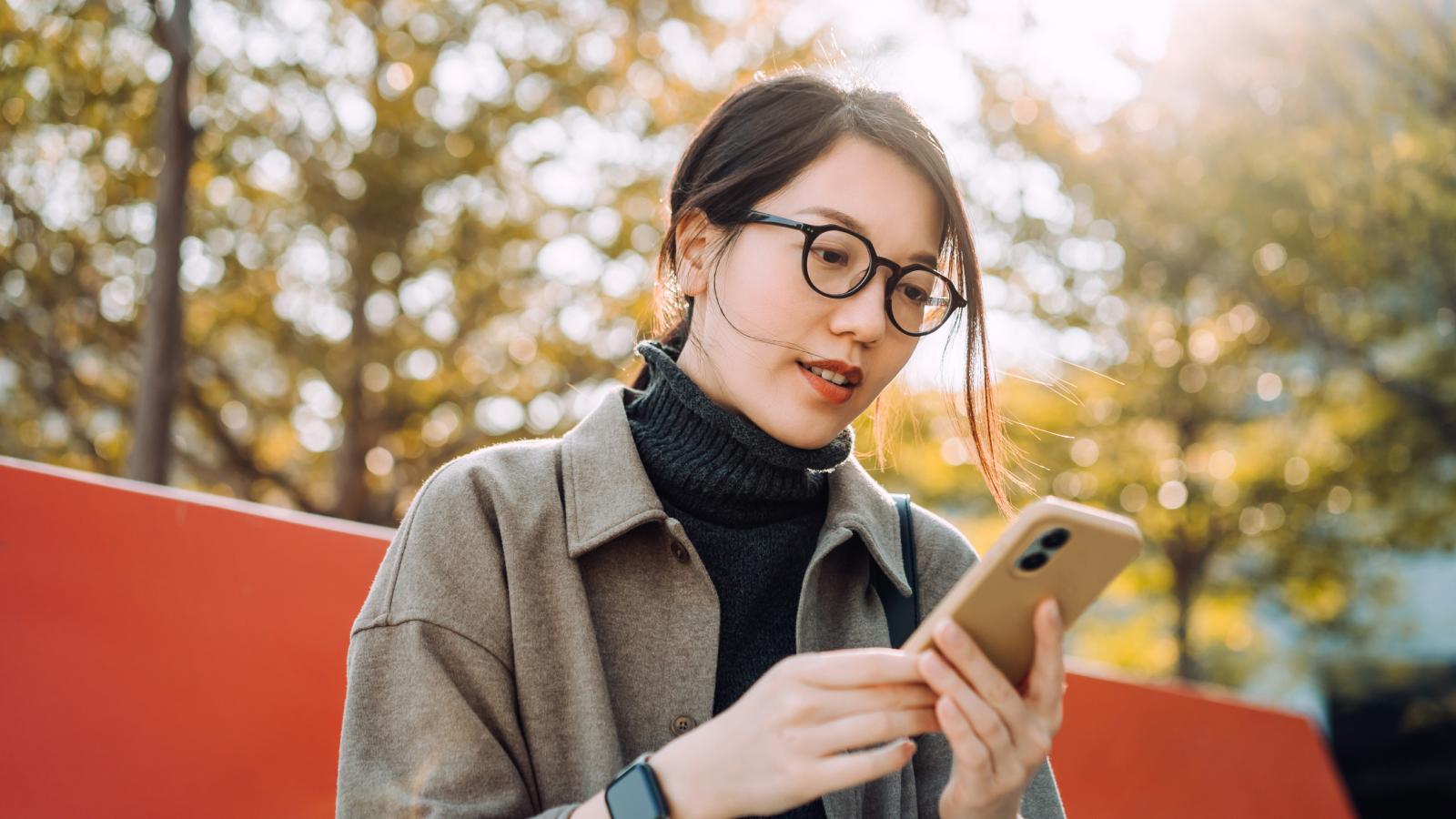 Woman with glasses holding phone