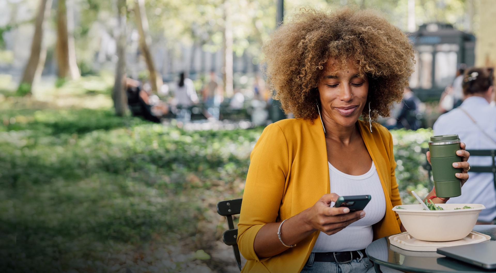 Brand employee landing page immersive hero image Woman checking her phone in Bryant Park while having lunch
