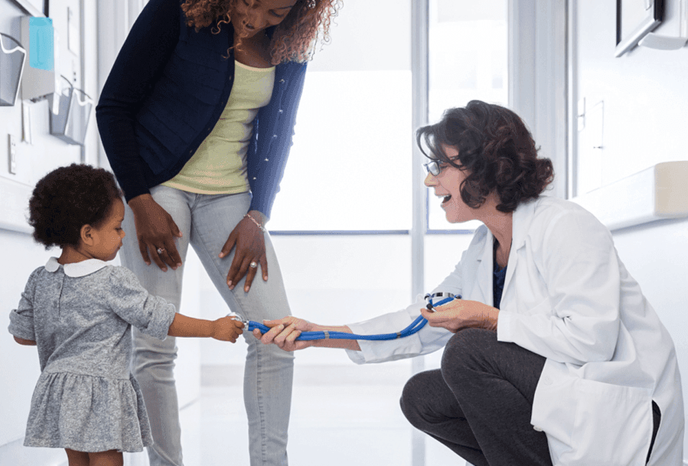 Little girl pulling on a doctors stethoscope.