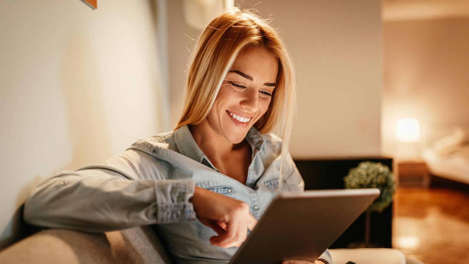 Woman sitting on the couch using a tablet.