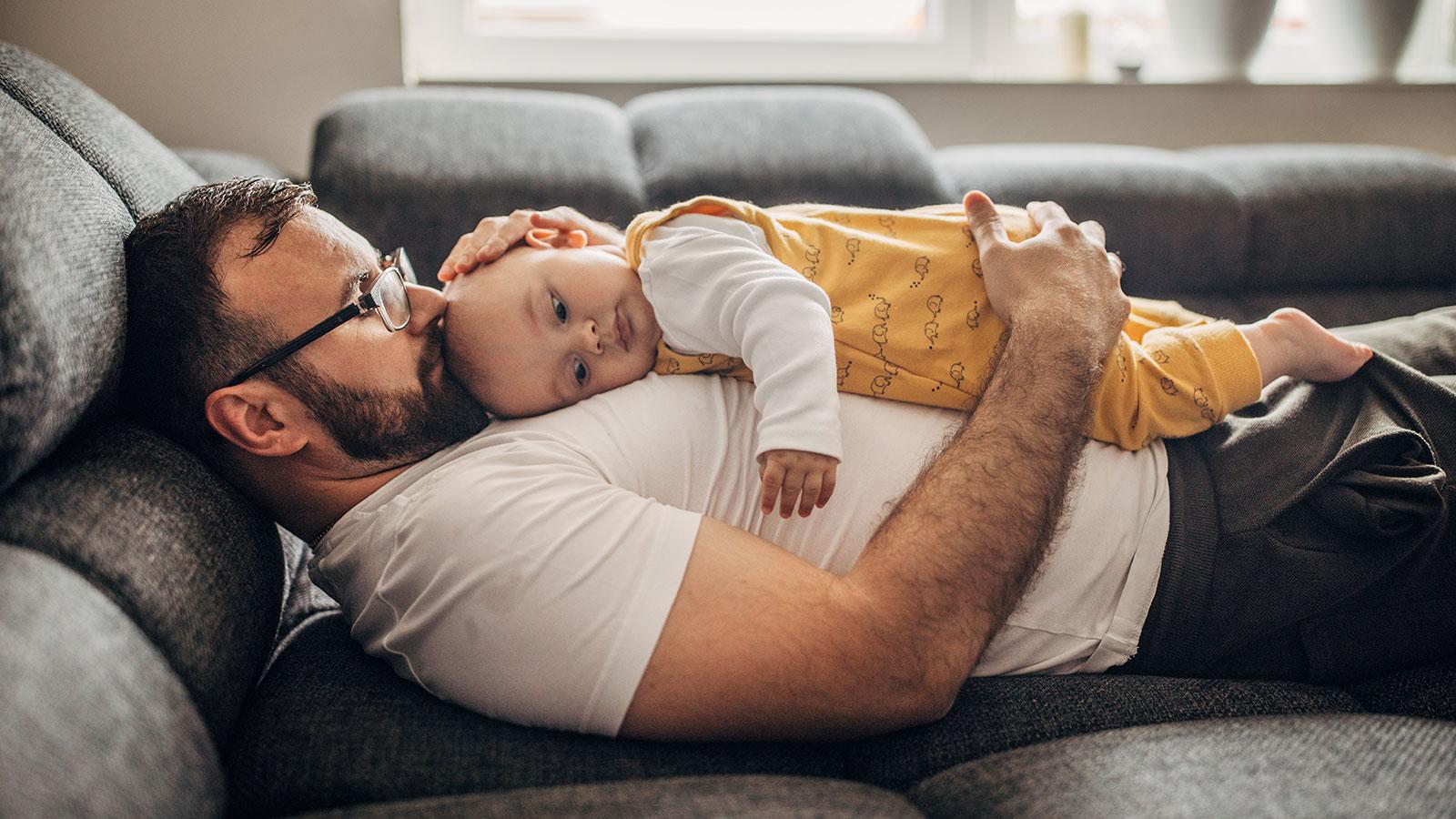 Father and baby son relaxing on sofa together