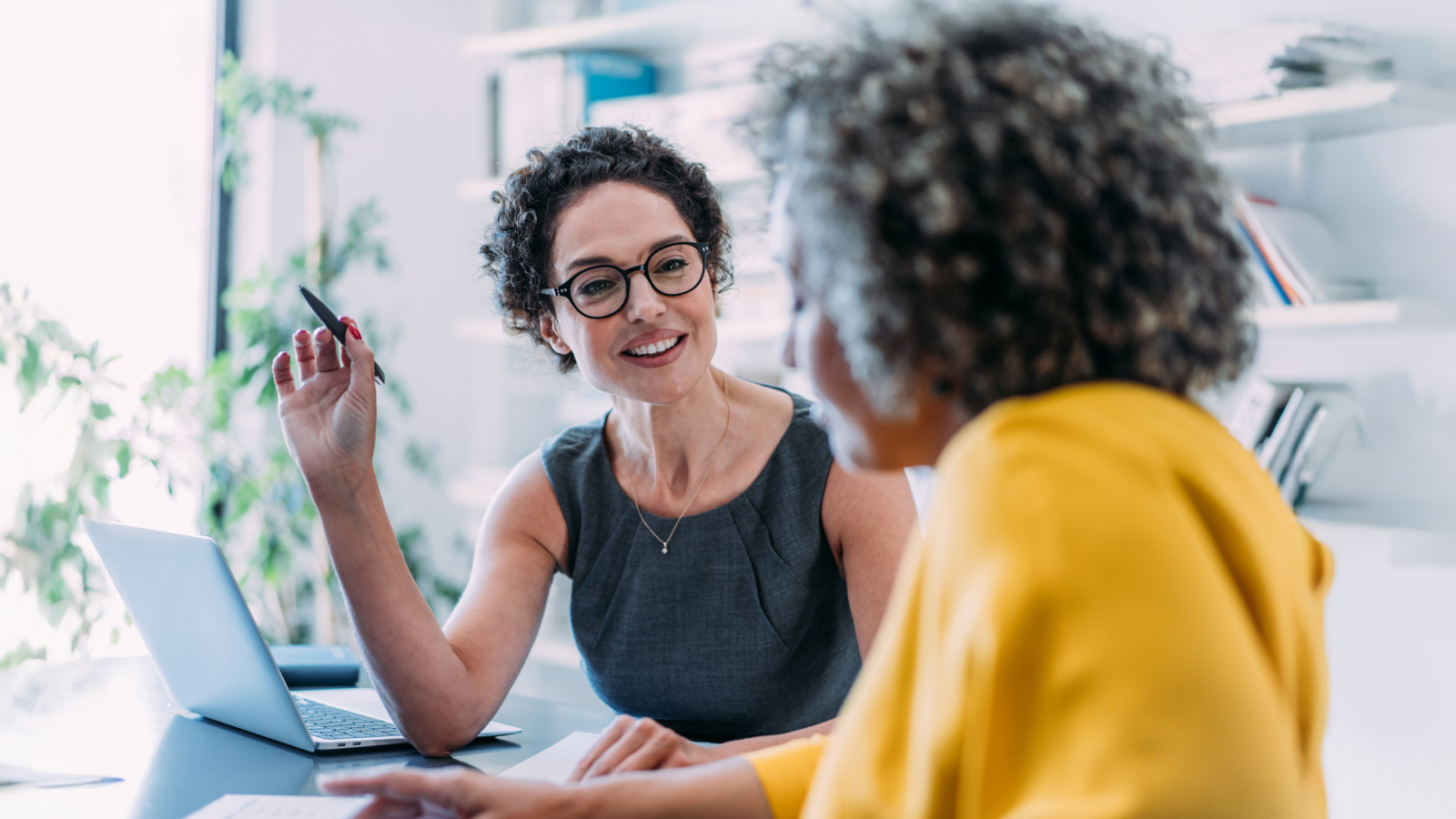 Two female colleagues talking to each other at an office. Two female colleagues talking to each other at an office.