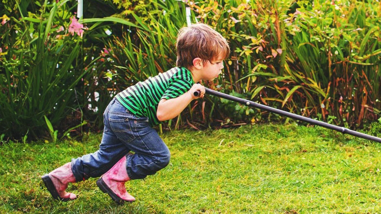 Little boy mowing the lawn