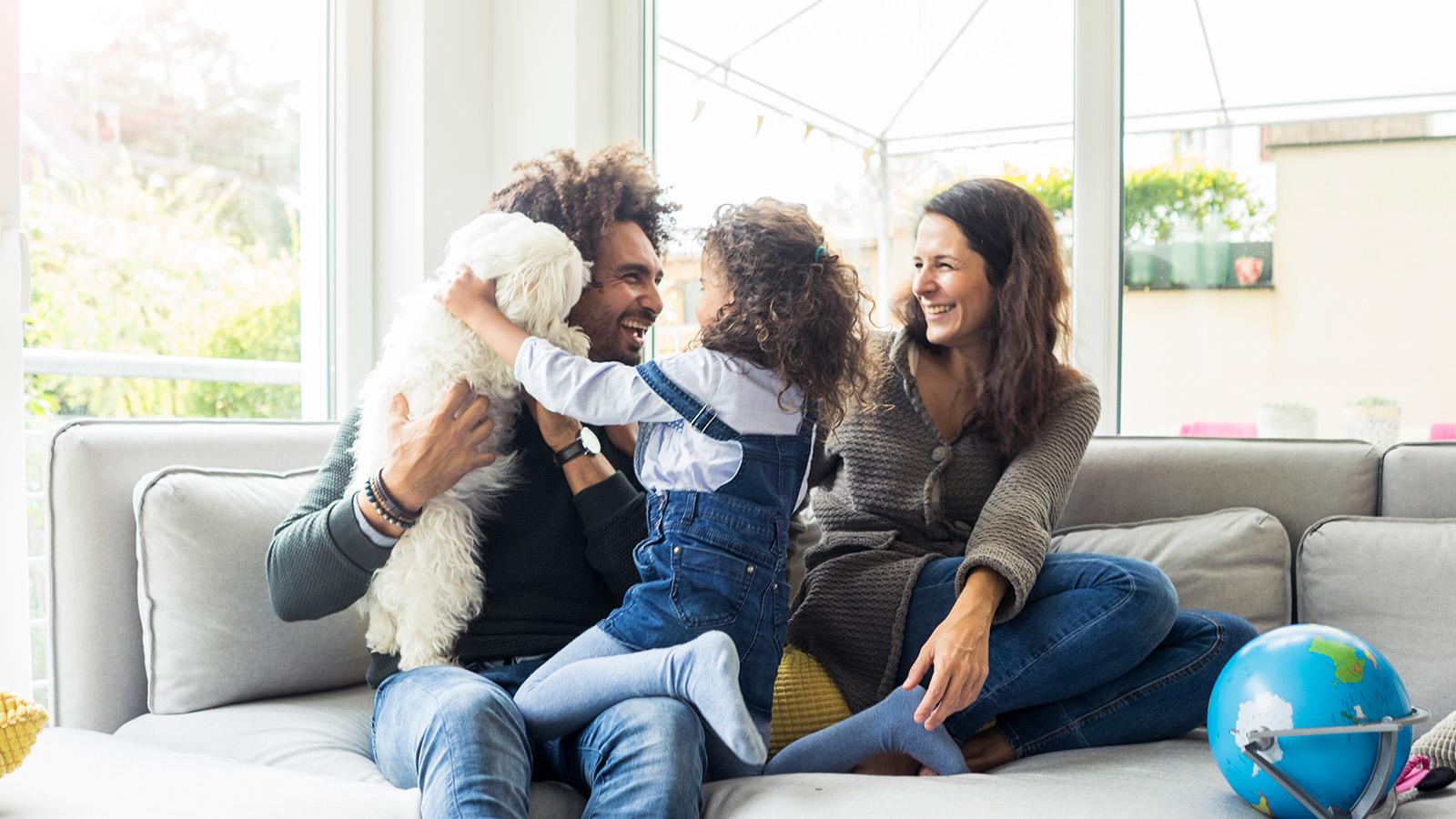 Family with their small dog playing together on the couch