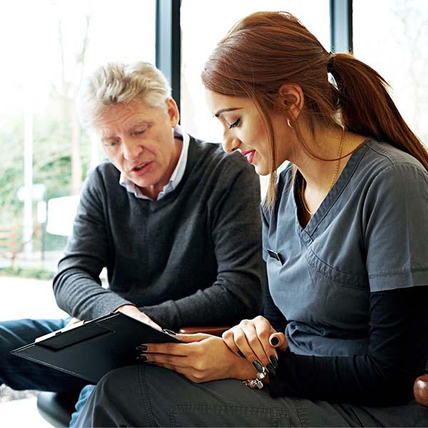 Female dentist reviewing notes with male patient.