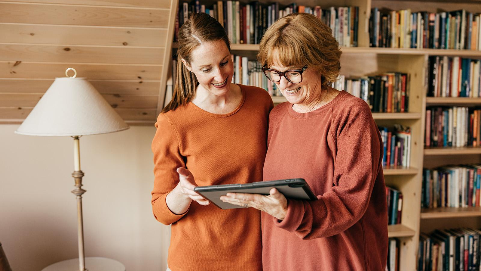 Young woman standing with her mother holding a tablet
