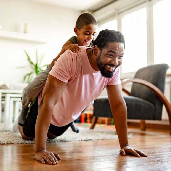 Father doing push ups with his son on his back.