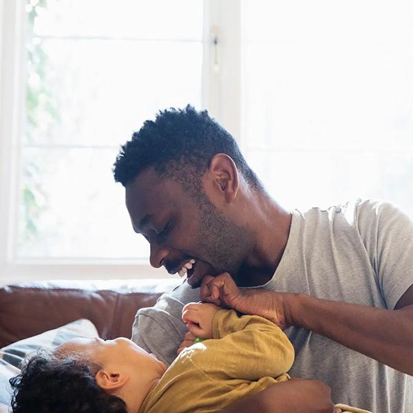 Man plays with child on the counch.