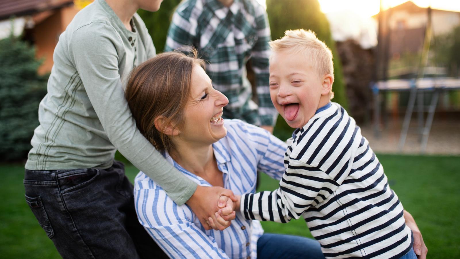 Mother and her son with down syndrome playing outside with family. Mother and her son with down syndrome playing outside with family.