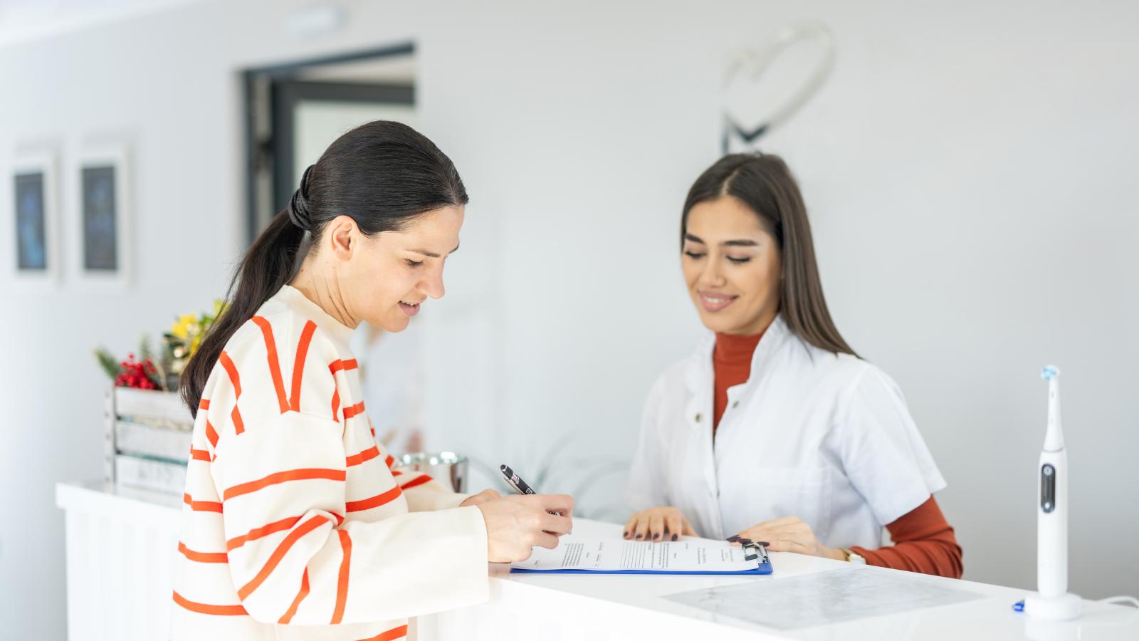 woman-checking-in-with-receptionist-at-dental-office-16x9-1600x900 woman-checking-in-with-receptionist-at-dental-office