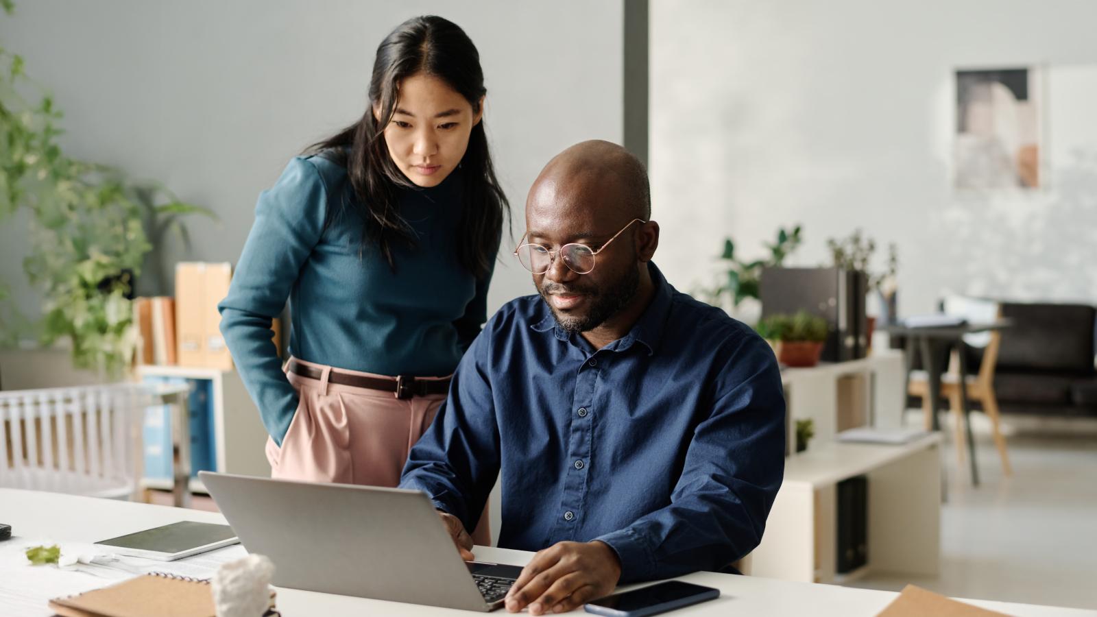 Asian woman and black man looking at laptop