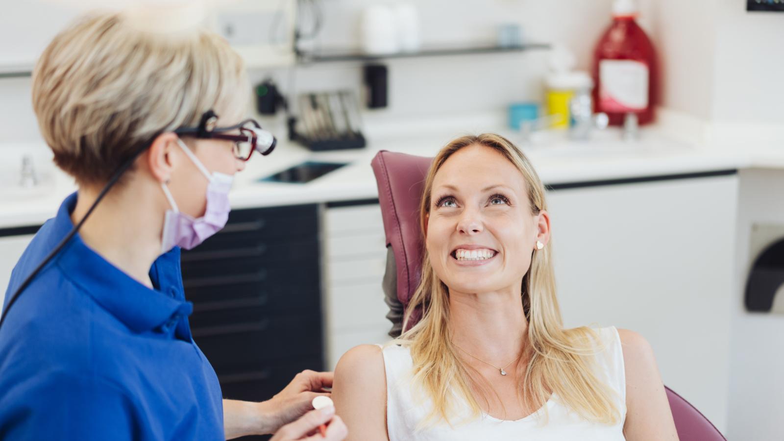 Dentist and patient in chair smiling at one another.
