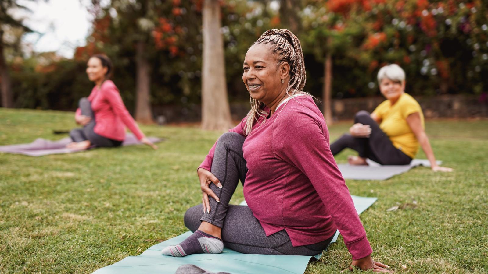 Older woman stretching in a yoga class outdoors