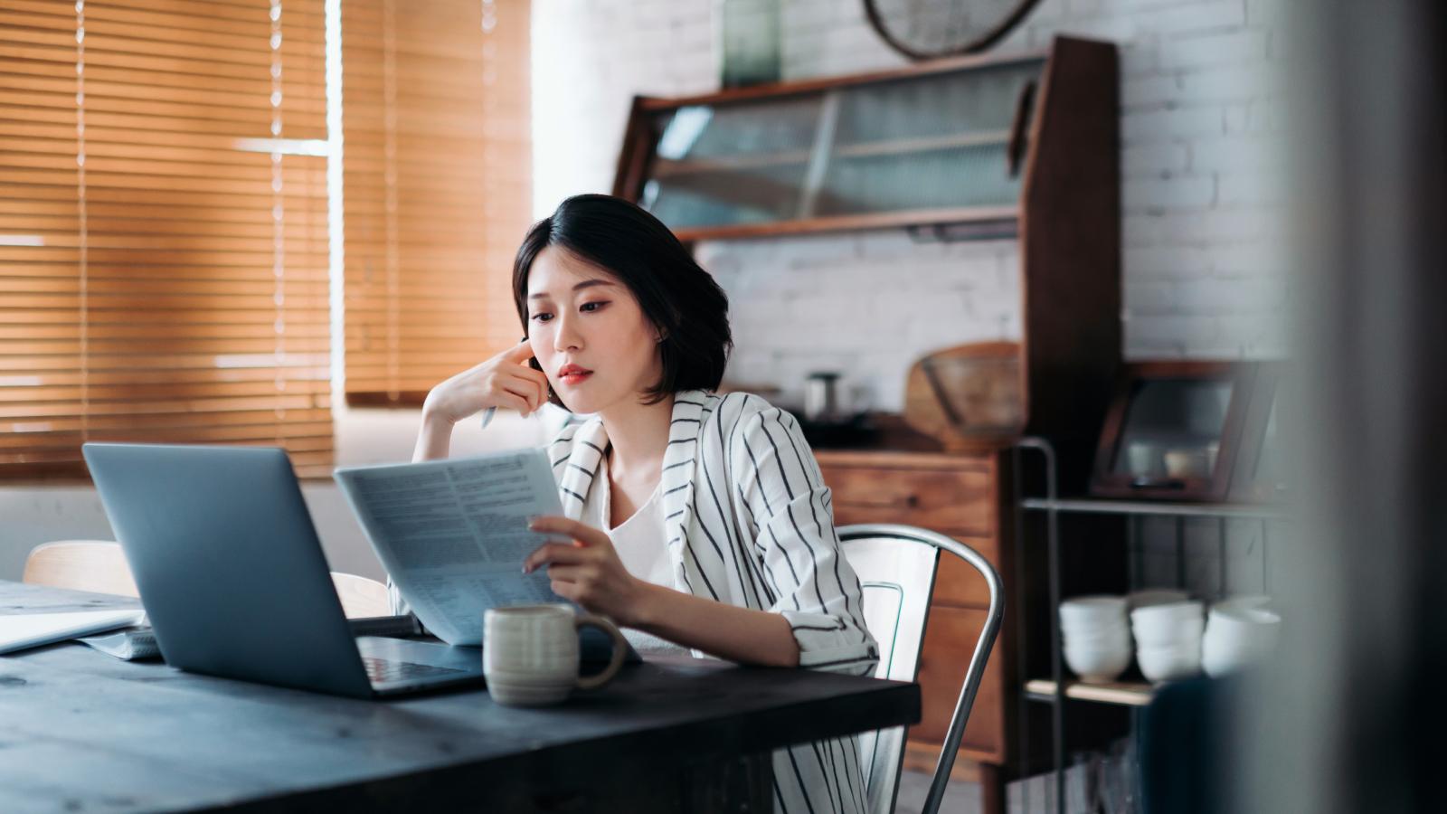 Woman working on laptop handling documents