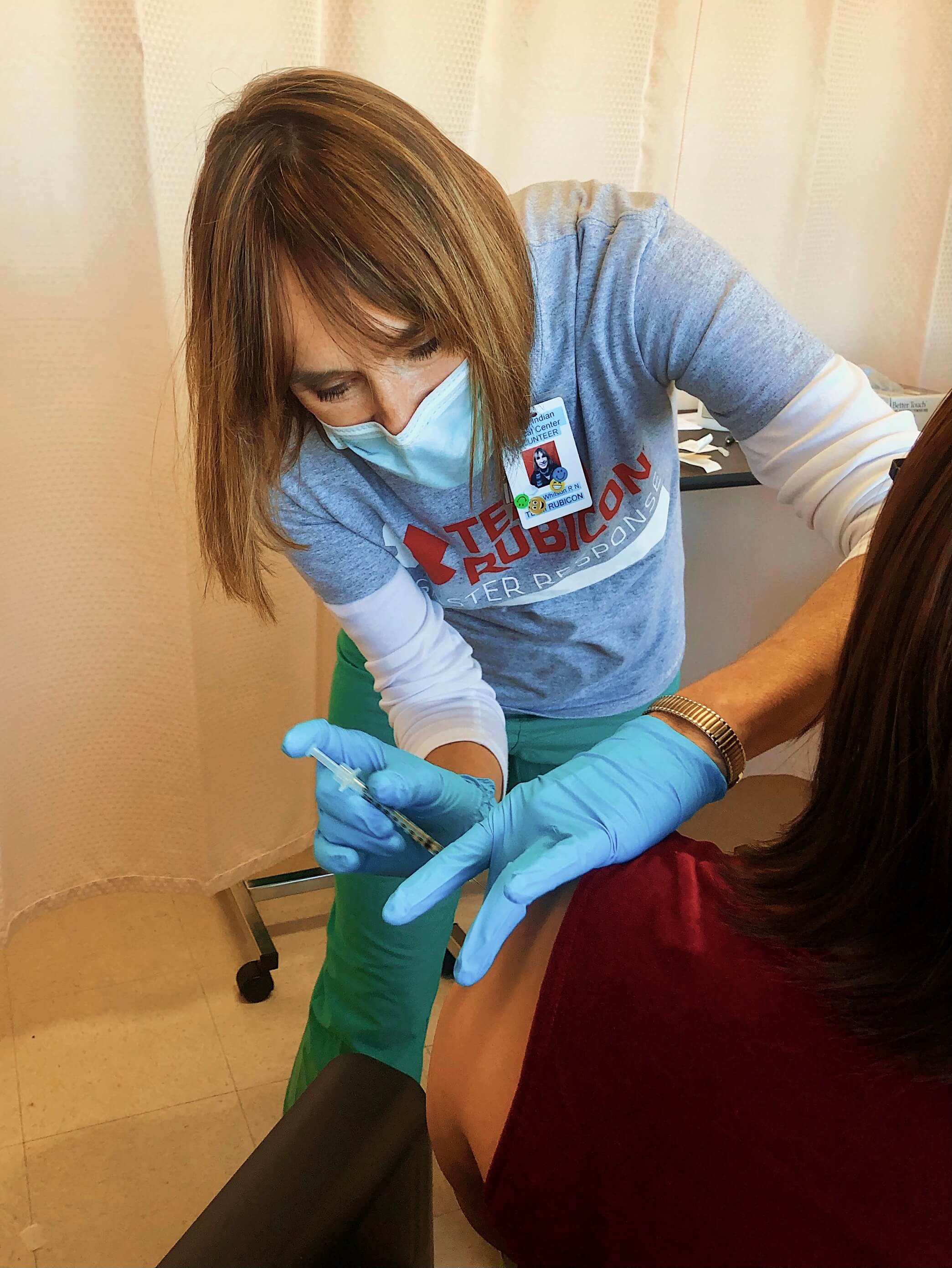 Nurse in mask administering COVID-19 vaccine