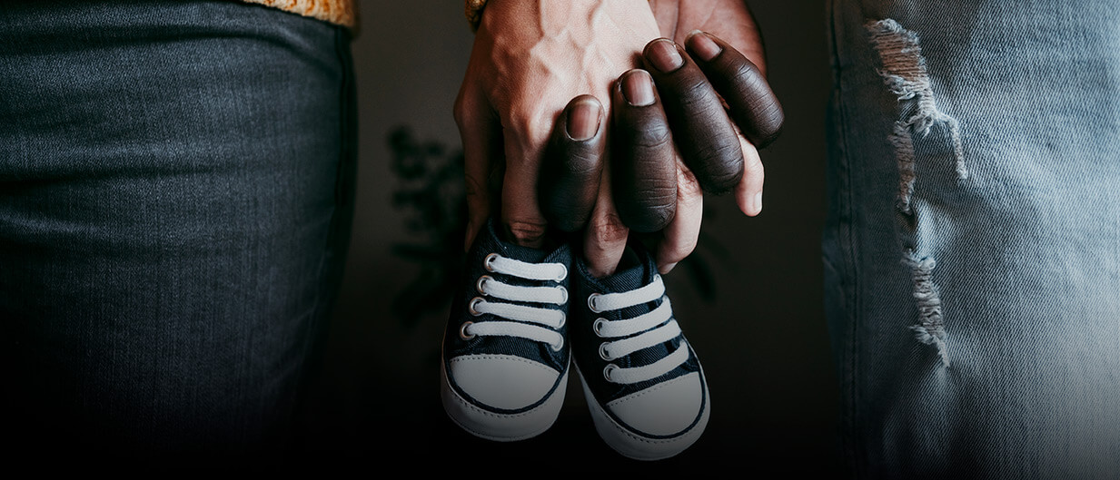 Couple holding hands and baby shoes