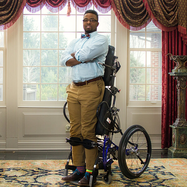 Dr. Feranmi Okanlami standing up in his wheelchair