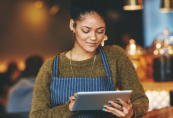 woman standing in her cafe looking at her tablet