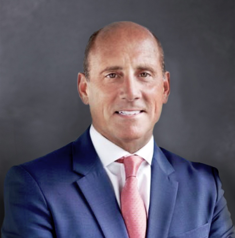 Jonathan Mayhew looks into the camera proudly, wearing a blue suit, white shirt and salmon colored tie. 