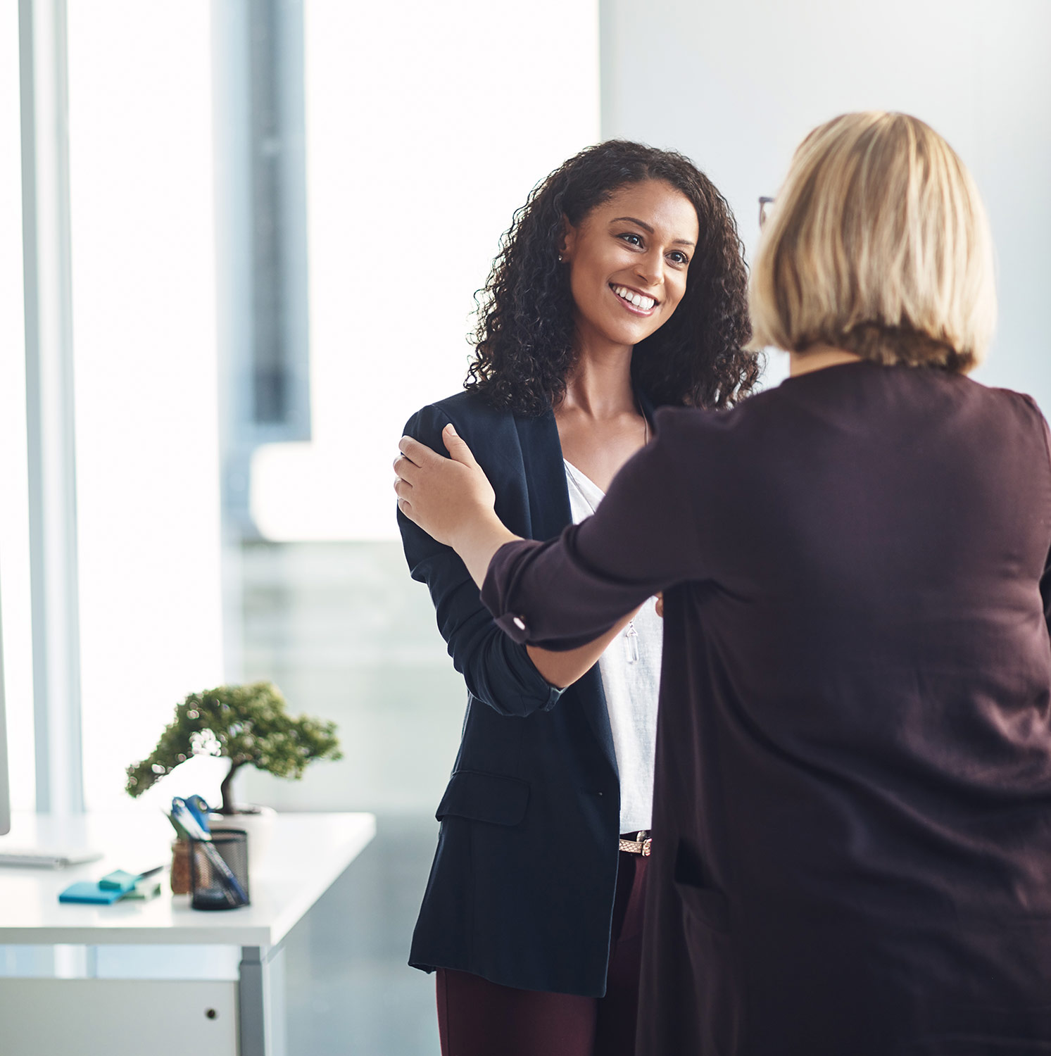 Woman smiling and shaking hands with another woman.