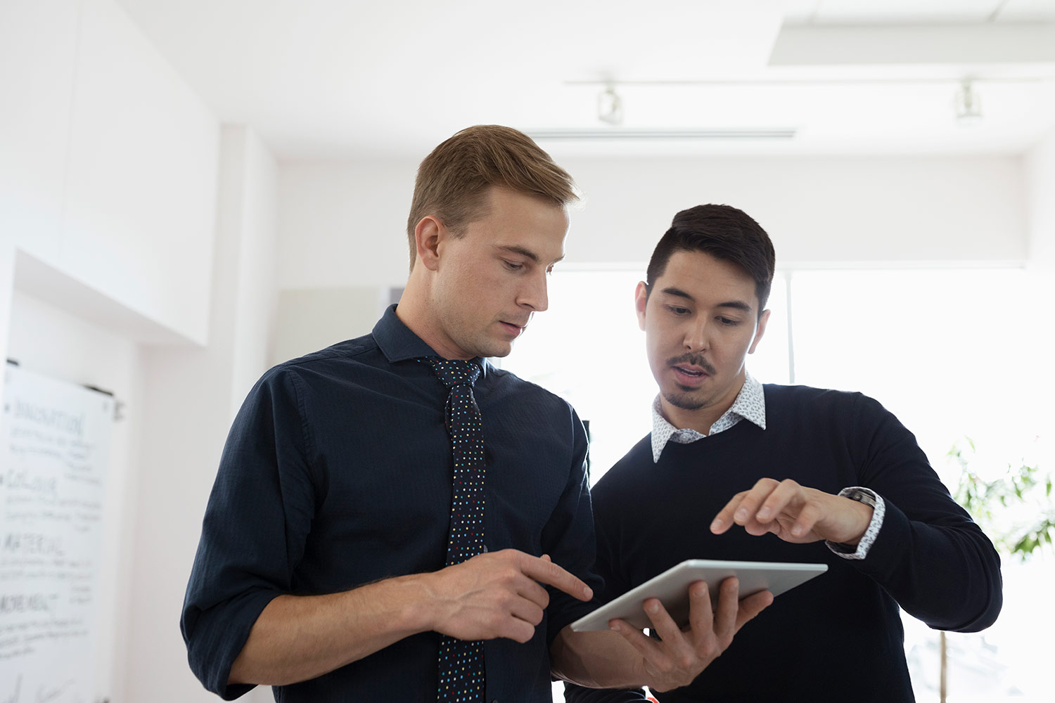 Two male employees looking over a tablet